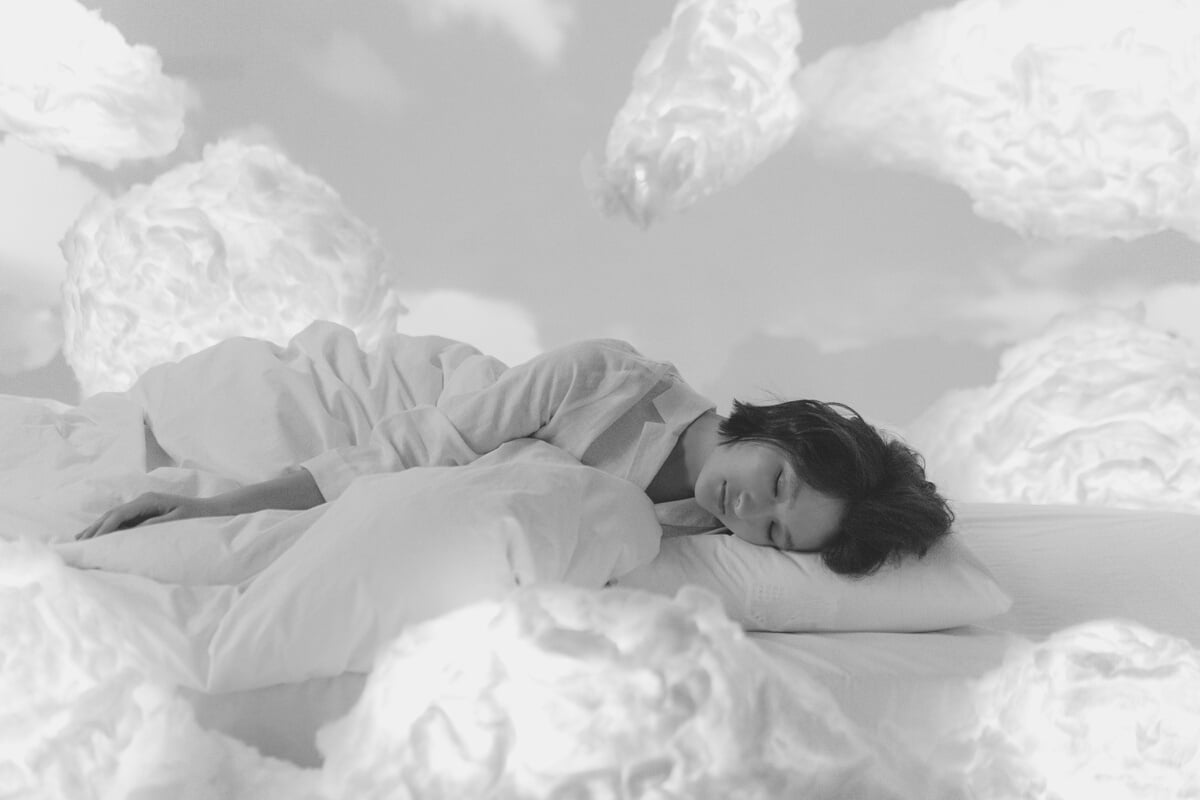 Photo of a Woman Sleeping Near Fluffy Clouds